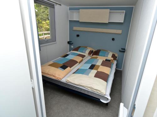a small bed in a room with a window at Mobile Home an der Drau in Sachsenburg