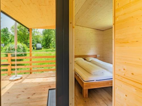 a bedroom in a wooden cabin with a bed on a deck at Wood Cube an der Drau in Sachsenburg