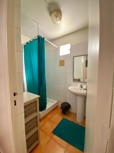 a bathroom with a blue shower curtain and a sink at Le jacquier in Goyave