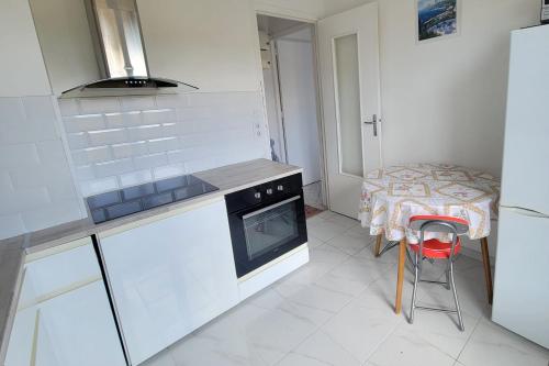 - une cuisine avec une cuisinière et une table avec un tabouret dans l'établissement Apartment in the heart of Saint-Raphaël, à Saint-Raphaël