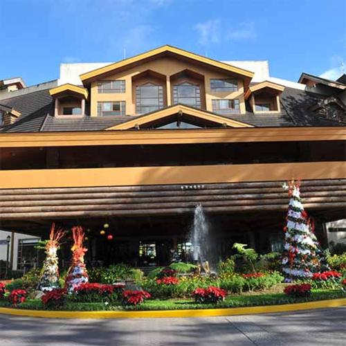 a building with a fountain in front of a garden at Private Room in Camp John Hay Baguio City in Baguio