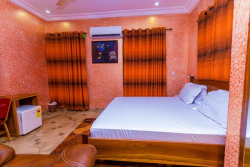 a bedroom with a large bed with orange curtains at Kobby Keach K Hotel in Kumasi