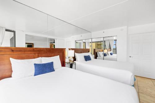 - 2 lits blancs dans une chambre avec un miroir dans l'établissement Waikiki Banyan T1-3106, à Honolulu