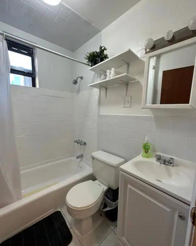 a white bathroom with a toilet and a sink at The 30 Day Stay Vibrant House in New York