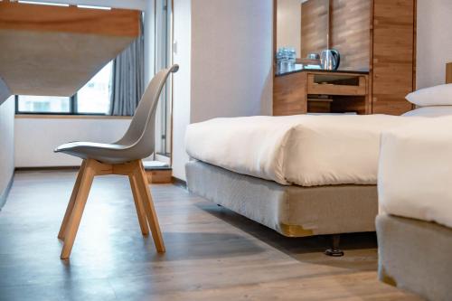 a chair sitting next to a bed in a room at 雲沐行旅 Hotel Cloud Arena-Daan in Taipei