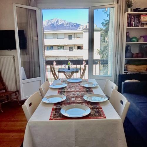 une table avec des chaises et des assiettes dessus avec une vue dans l'établissement Vue Imprenable - Calme & Equipé avec parking Privé, à Grenoble