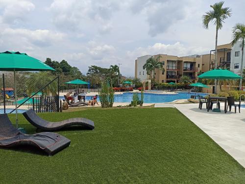 a resort with a pool with chairs and umbrellas at Apartamento cómodo, luz natural, zonas comunes, piscinas traer gorro, wifi, parqueadero en el Quindío in La Tebaida