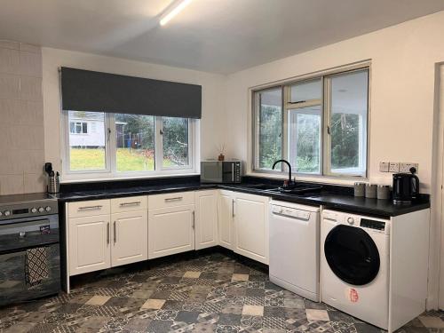 a kitchen with white cabinets and a sink and windows at Shared House in central location Inverness in Inverness