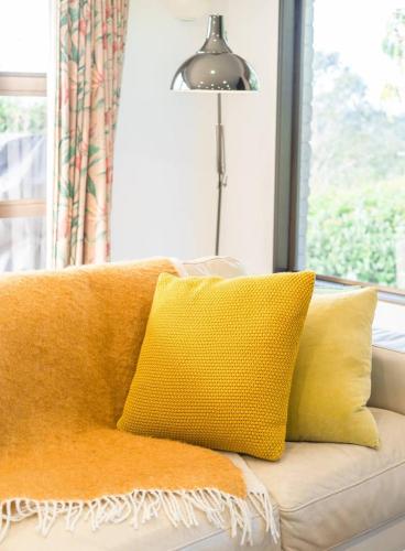 a couch with yellow pillows and a lamp and a window at Foley Retreat in Dairy Flat
