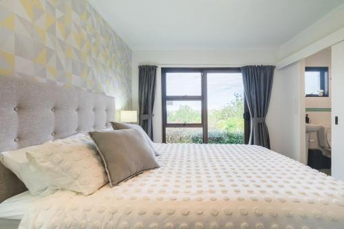 a bedroom with a large white bed with a window at Foley Retreat in Dairy Flat