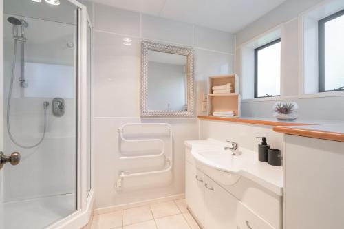 a white bathroom with a shower and a sink at Foley Retreat in Dairy Flat