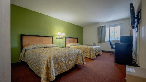 2 camas en una habitación de hotel con paredes verdes en THE INN-Pittsburgh, en Pittsburgh