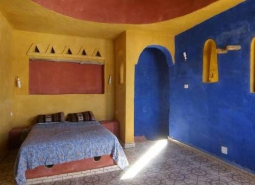 een slaapkamer met een bed met blauwe en gele muren bij Djerba Advent in Bou Menjel
