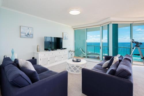 a living room with a blue couch and a television at The Waterford on Main Beach in Gold Coast
