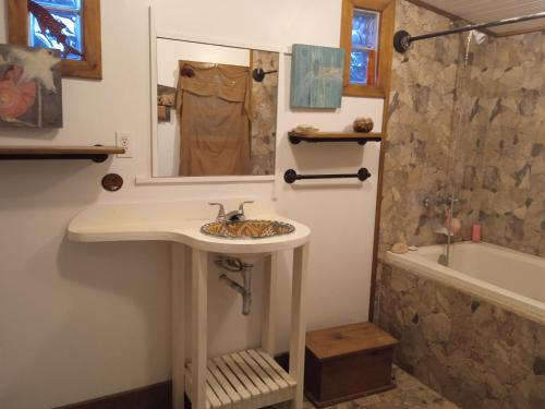 a bathroom with a sink and a mirror and a tub at casa de huéspedes selvatica in Utila