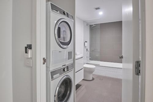 a bathroom with a washer and dryer and a toilet at Quest Cannon Hill in Brisbane