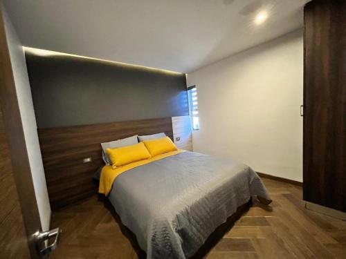een slaapkamer met een groot bed met gele kussens bij Departamento las huertas in Cuauhtémoc