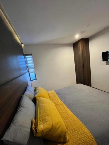 - une chambre avec un lit et des oreillers jaunes dans l'établissement Departamento las huertas, à Cuauhtémoc