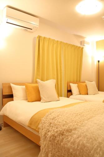 two beds in a room with yellow curtains at Casa Stella 3 Sagittarius by Liaison in Osaka
