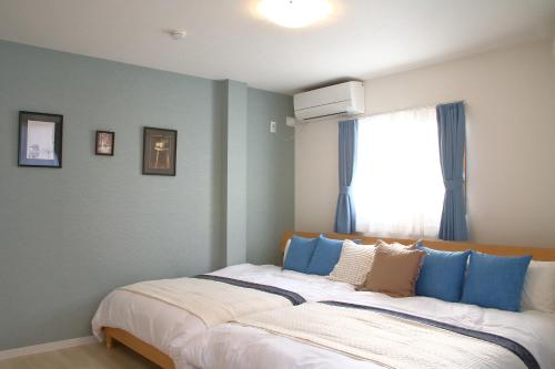 a bedroom with a bed with blue pillows and a window at Casa Stella 3 Sagittarius by Liaison in Osaka