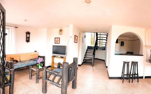 een woonkamer met een bank en een tv bij Finca con espectacular zona verde y hermosa vista a la piedra in Guatapé