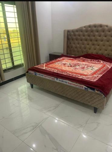 Bahria town karachi في كراتشي: غرفة نوم مع سرير مع بطانية حمراء عليه