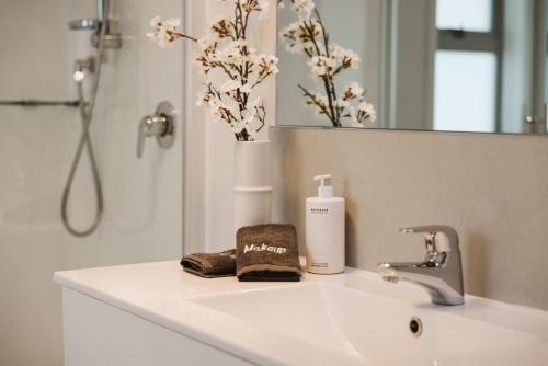 a bathroom sink with a bottle of soap and a mirror at Seaside Bliss Your Coastal Haven in Mount Maunganui