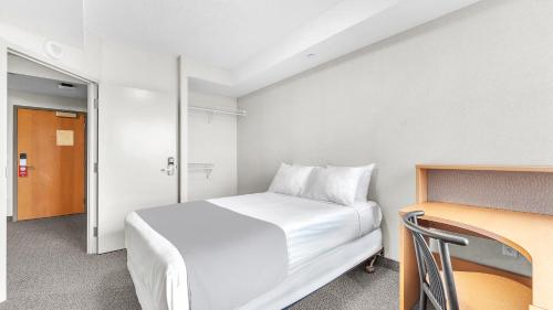 a small bedroom with a white bed and a desk at Residence & Conference Centre - London in London