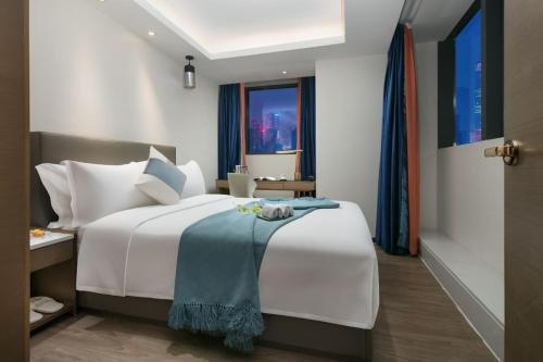 a bedroom with a white bed with a blue blanket on it at Changsha Zealandia Serviced Apartment in Changsha