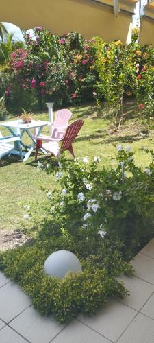 Ein paar Stühle stehen in einem Garten mit Blumen in der Unterkunft Zen paradise in Sainte-Anne