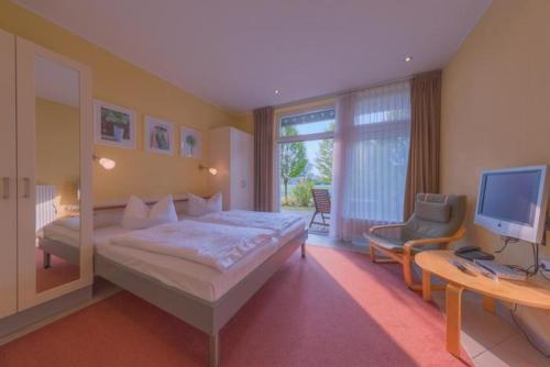 a bedroom with a bed and a television and a desk at Strandläufer 114 in Granzow