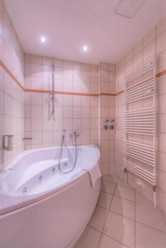 a white bath tub in a bathroom with tiles at Strandläufer Classic 101 in Granzow