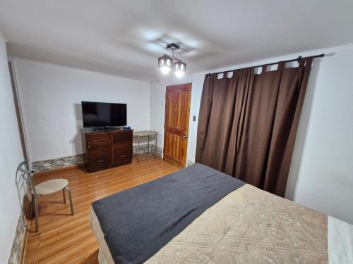 a bedroom with a bed and a flat screen tv at Hosteria Piedra Blanca in Taltal