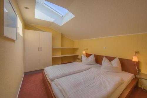 a bedroom with a large white bed with a skylight at Schneeeule 201 in Granzow