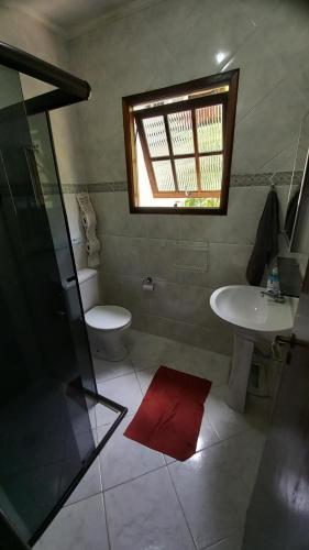un bagno con lavandino, WC e finestra di Casa 84 Condomínio fechado de frente para praia - Boiçucanga SP a São Sebastião