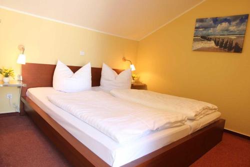 a bedroom with a large bed with white pillows at Schneeeule 209 in Granzow