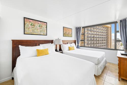 two beds in a hotel room with a window at Waikiki Banyan T1-3204 in Honolulu