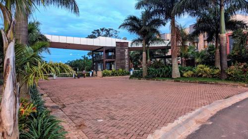 a brick road in front of a building with palm trees at Bella Vista in Wakiso