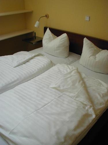 two beds in a hotel room with white sheets and pillows at Schneeeule 225 in Granzow