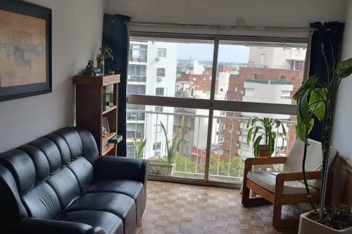 a living room with a couch and a large window at Apto Centrico Zona Tres Cruces in Montevideo