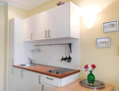 a kitchen with white cabinets and a vase of flowers on a table at Schneeeule 223 in Granzow