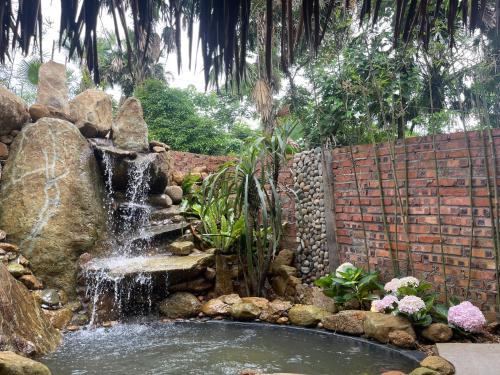 a waterfall in a garden with a stone wall at Pu Luong Paradise in Hương Bá Thước