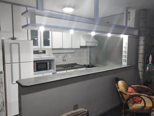 a kitchen with white cabinets and a counter top at Apto Enseada Guarujá in Guarujá