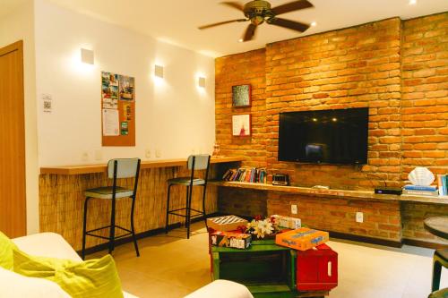 a living room with a bar with stools and a tv at Palace Beach Hostel in Rio de Janeiro
