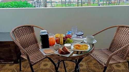 una mesa con comida para el desayuno con dos sillas en Pousada Maceió é Massa Praia de Pajuçara en Maceió