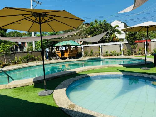 a large swimming pool with an umbrella and grass at Balai Roco in Bauang