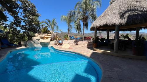 a swimming pool in a resort with a thatch roof at Villas Chulavista in Sayulita