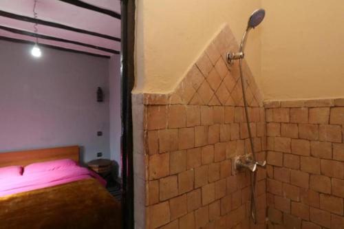 a bedroom with a brick wall and a shower at Locanda Lodge, Marrakech Tacheddirt in Marrakech