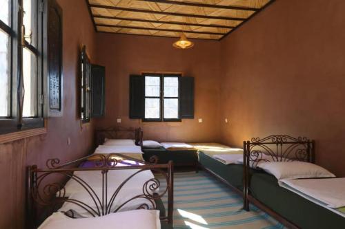 a room with four beds in it with windows at Locanda Lodge, Marrakech Tacheddirt in Marrakech