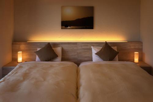 two beds in a hotel room with two lights at Hotel Miyajima Villa in Miyajima